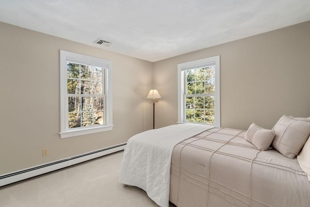 carpeted bedroom featuring a baseboard heating unit and visible vents