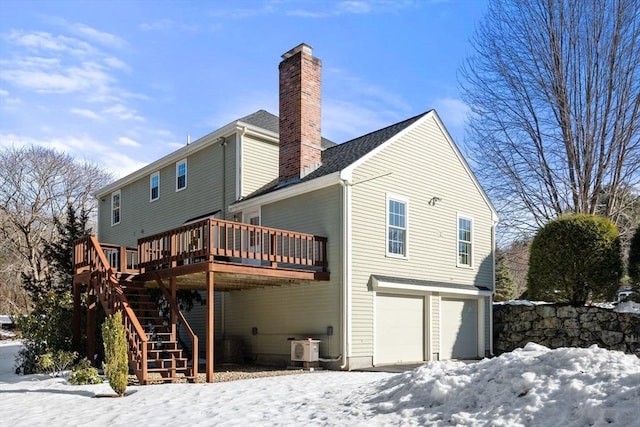 snow covered property with stairs, a deck, a chimney, and an attached garage