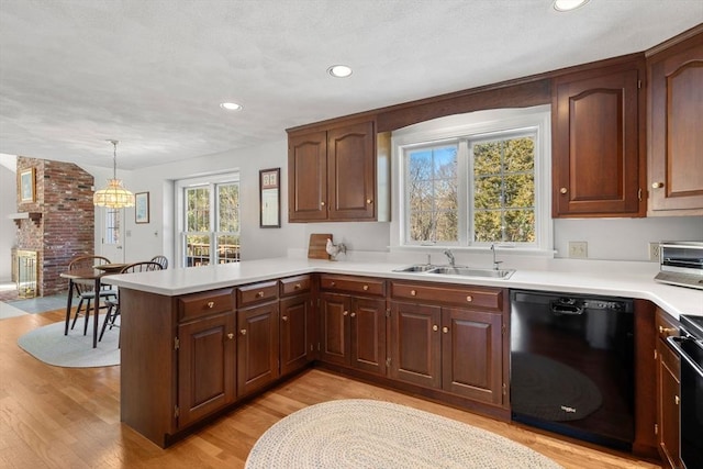 kitchen with light countertops, light wood-style flooring, a sink, dishwasher, and a peninsula