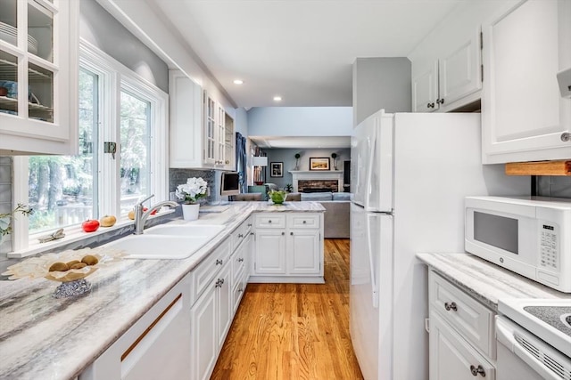 1441 Old Post Rd, Barnstable, MA 02648 - kitchen with white appliances, light wood-type flooring, white cabinetry, a fireplace, and glass insert cabinets