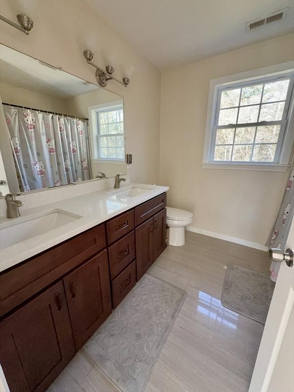 99 Dudley Rd, Oxford, MA 01540 - bathroom with toilet, double vanity, baseboards, and a shower with curtain