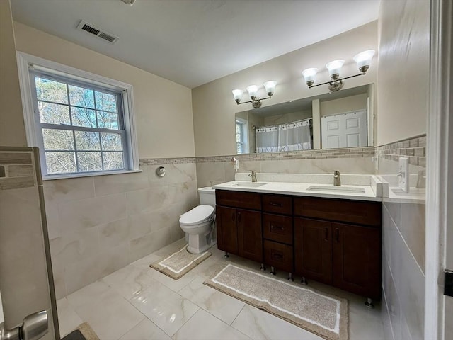 99 Dudley Rd, Oxford, MA 01540 - full bathroom featuring tile walls, toilet, double vanity, marble finish floors, and a wainscoted wall