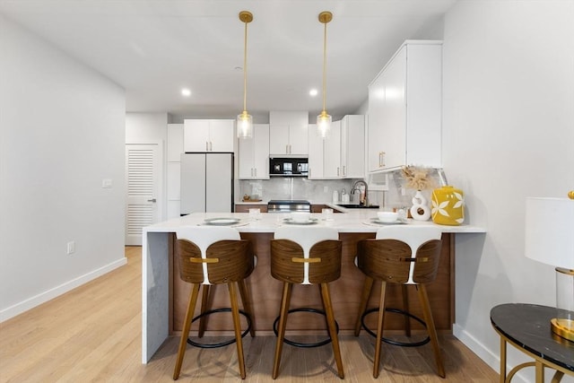 kitchen with white cabinetry, sink, a kitchen bar, hanging light fixtures, and white fridge