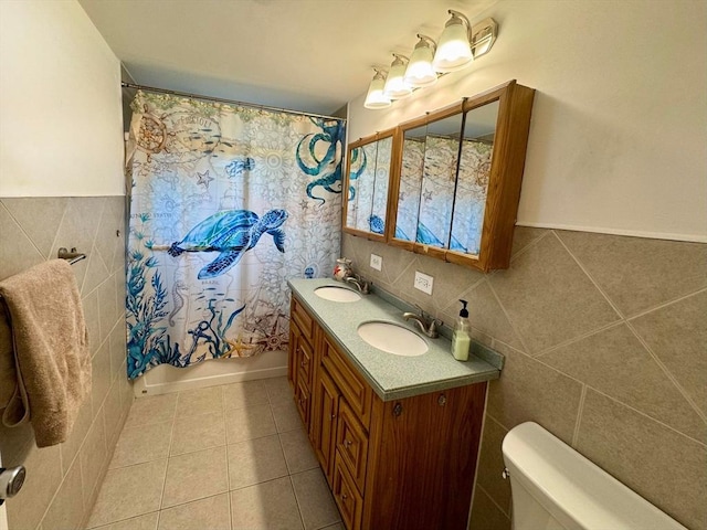 bathroom with tile walls, toilet, tile patterned flooring, and a sink