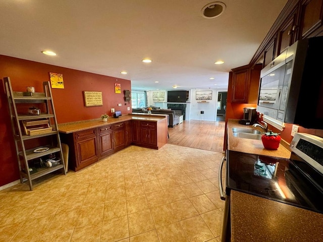 kitchen featuring recessed lighting, a sink, a fireplace, appliances with stainless steel finishes, and open floor plan