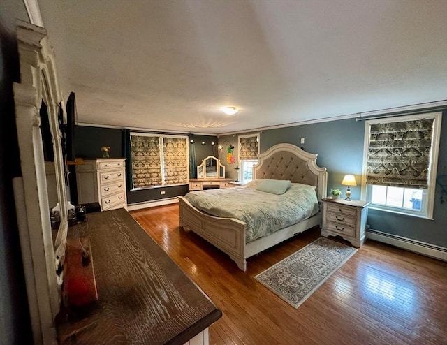 bedroom featuring baseboards, dark wood-style flooring, crown molding, and a baseboard radiator