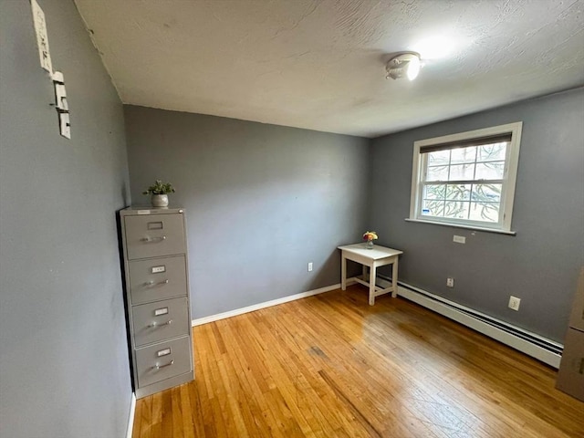 unfurnished bedroom featuring light wood finished floors, baseboards, and a baseboard radiator
