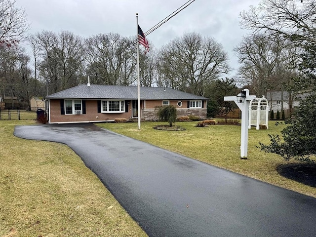 single story home featuring fence, aphalt driveway, a front lawn, and stone siding
