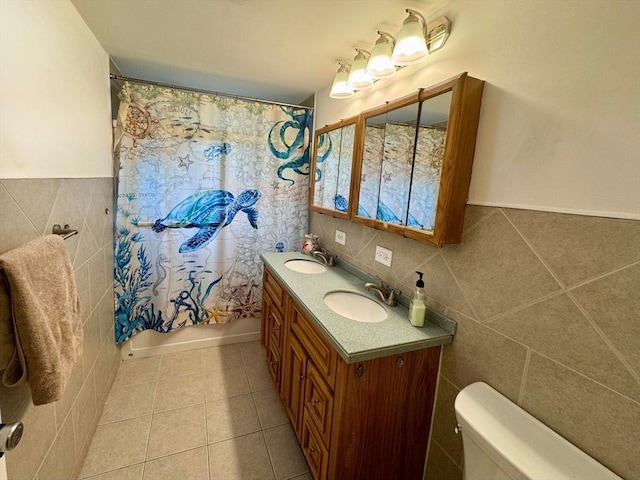 bathroom featuring tile walls, toilet, tile patterned flooring, and a sink