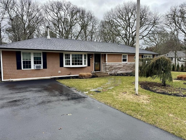 single story home featuring a front yard, a shingled roof, driveway, stone siding, and entry steps