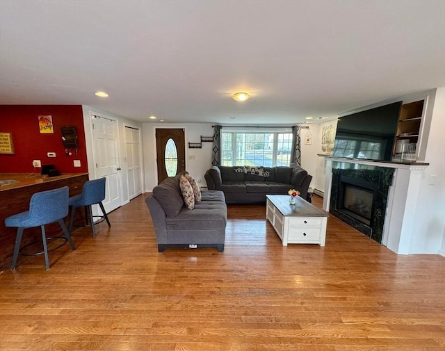 living room with a premium fireplace, recessed lighting, and light wood finished floors