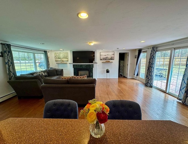 living area featuring recessed lighting, wood finished floors, baseboard heating, a fireplace, and baseboards