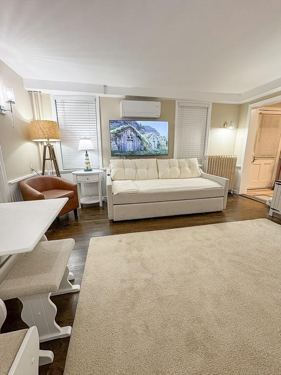 living room with an AC wall unit and dark wood-type flooring