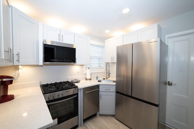 kitchen featuring sink, white cabinets, light hardwood / wood-style flooring, and stainless steel appliances