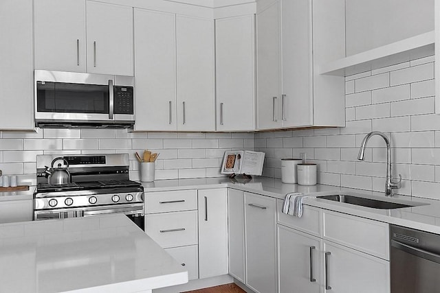 kitchen featuring decorative backsplash, appliances with stainless steel finishes, white cabinetry, and sink