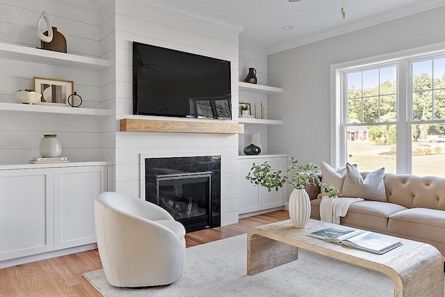 living room with built in shelves, light hardwood / wood-style floors, and crown molding