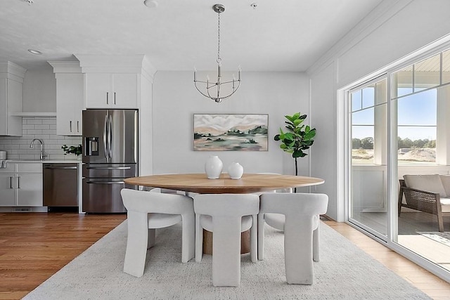 dining area with hardwood / wood-style flooring, sink, and an inviting chandelier