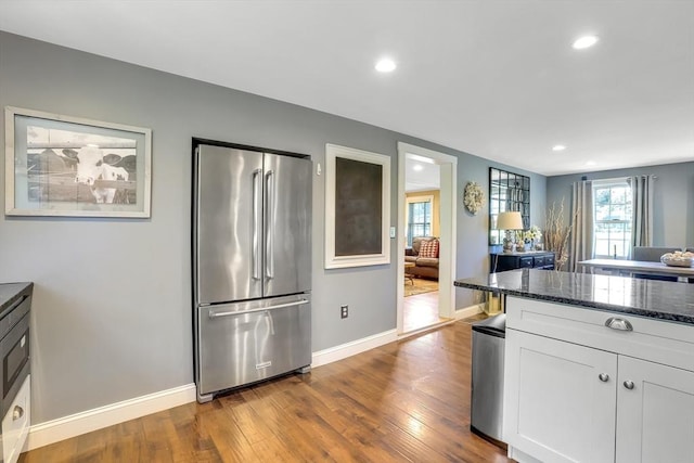 kitchen featuring high end fridge, dark wood-style flooring, dark stone counters, white cabinets, and recessed lighting