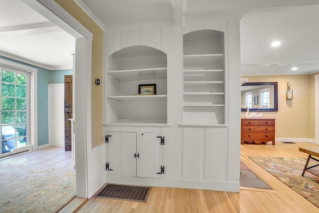 hall with light wood-style floors, baseboards, built in features, ornamental molding, and recessed lighting