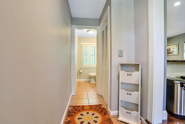 corridor featuring light tile patterned flooring and baseboards