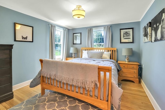 bedroom featuring baseboards, light wood-type flooring, and crown molding