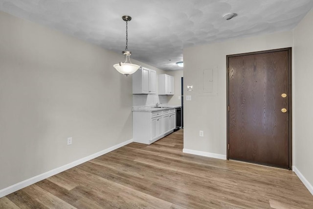 50 Juniper Rd Unit 1C, North Attleboro, MA 02760 - kitchen featuring white cabinets, light wood finished floors, baseboards, light countertops, and a sink