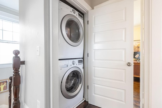 clothes washing area featuring laundry area, dark wood-type flooring, and stacked washer and clothes dryer