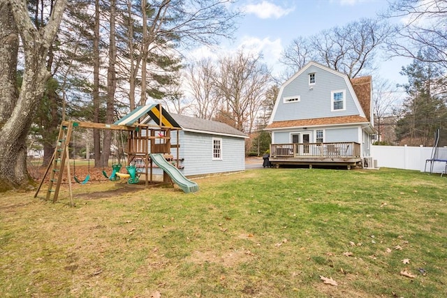 back of property featuring a playground, fence, a gambrel roof, a lawn, and a wooden deck