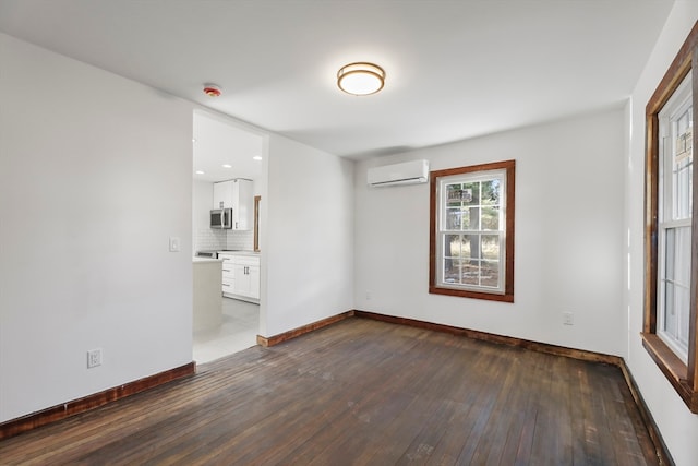 unfurnished room featuring an AC wall unit and dark wood-type flooring