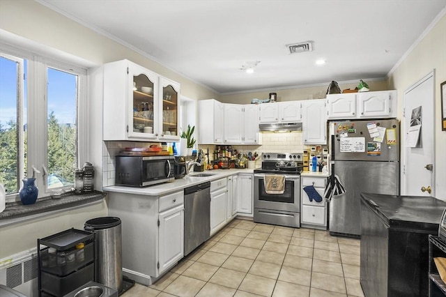 kitchen with light tile patterned floors, sink, appliances with stainless steel finishes, white cabinetry, and ornamental molding