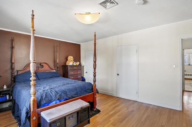 bedroom featuring crown molding, radiator, and light wood-type flooring