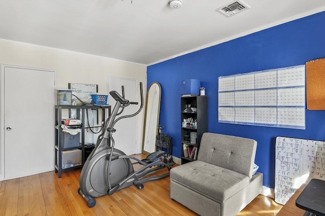 exercise area with wood-type flooring and crown molding