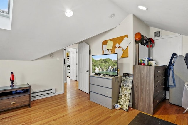 additional living space with lofted ceiling, a baseboard heating unit, and light hardwood / wood-style flooring