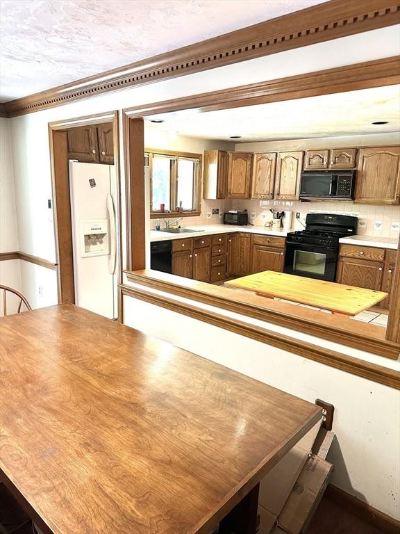 117 Metropolitan Ave Unit 117, Ashland, MA 01721 - kitchen featuring black appliances, light countertops, and brown cabinetry