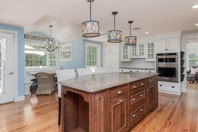 8 Whitaker Ln, Groton, MA 01450 - kitchen with double oven, light wood-style floors, white cabinetry, tasteful backsplash, and a breakfast bar area