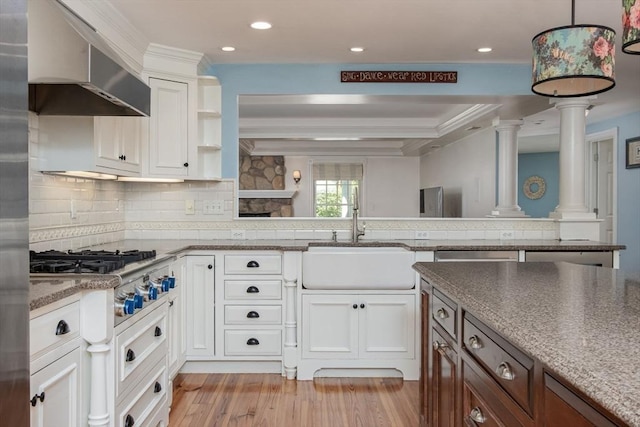8 Whitaker Ln, Groton, MA 01450 - kitchen with ornate columns, wall chimney exhaust hood, a sink, light wood-style floors, and stainless steel gas stovetop