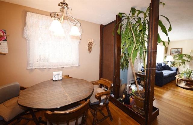 dining room with a notable chandelier, baseboard heating, and wood finished floors