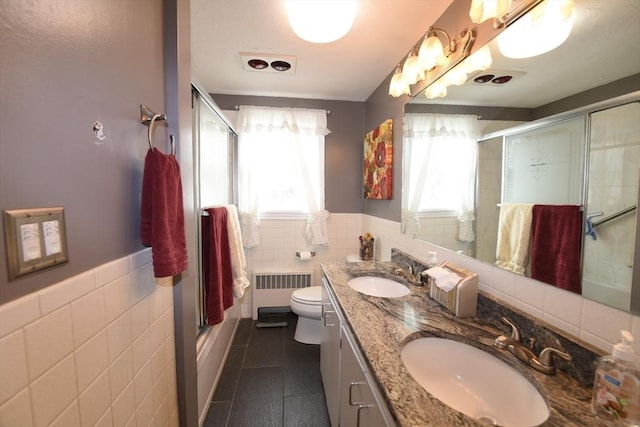 bathroom with toilet, radiator heating unit, a sink, and tile walls