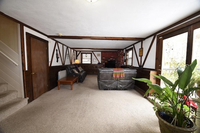 living area featuring light carpet, stairs, and beam ceiling