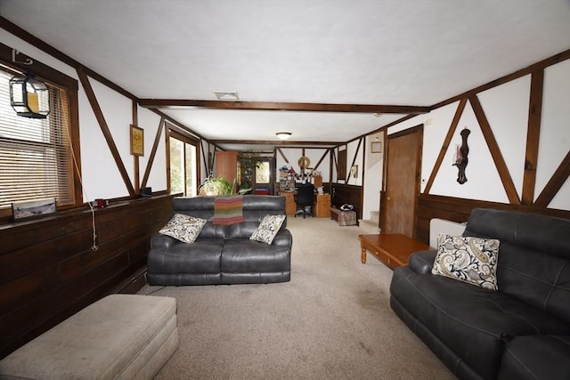 carpeted living room featuring wood walls, visible vents, and beamed ceiling