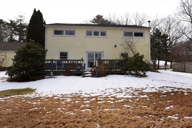 snow covered back of property featuring a deck