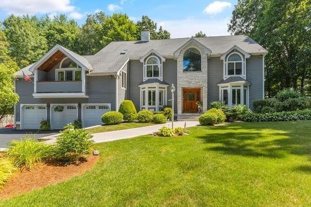 view of front facade featuring a chimney, a garage, a front lawn, and aphalt driveway