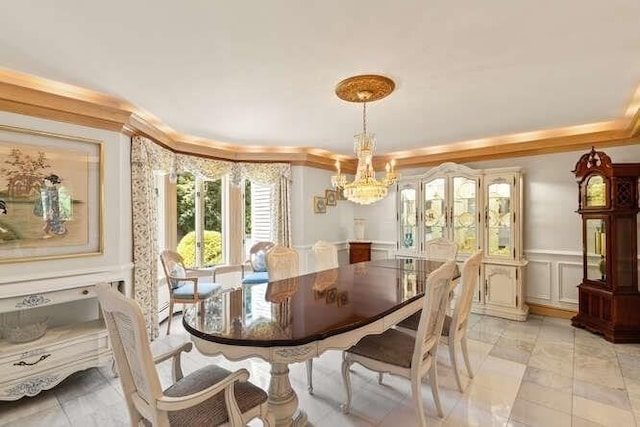 dining area featuring a decorative wall, a notable chandelier, crown molding, and a wainscoted wall