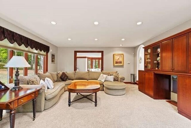 living area with baseboards, recessed lighting, and light carpet