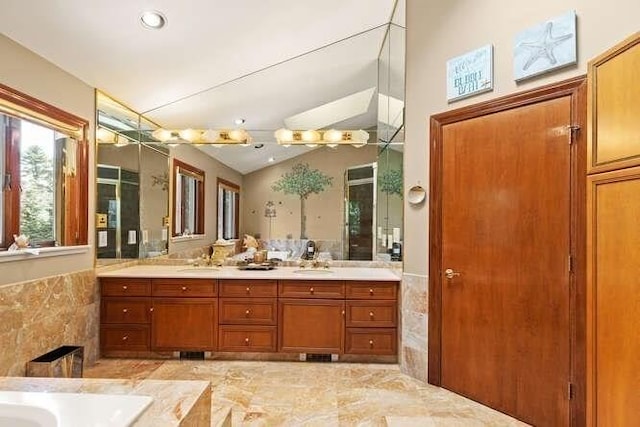 full bath featuring a sink, a washtub, double vanity, and lofted ceiling