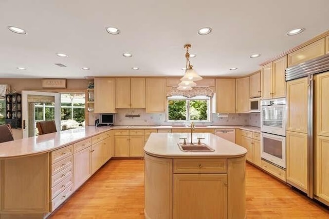 kitchen featuring light wood-style floors, white appliances, a peninsula, light countertops, and light brown cabinets