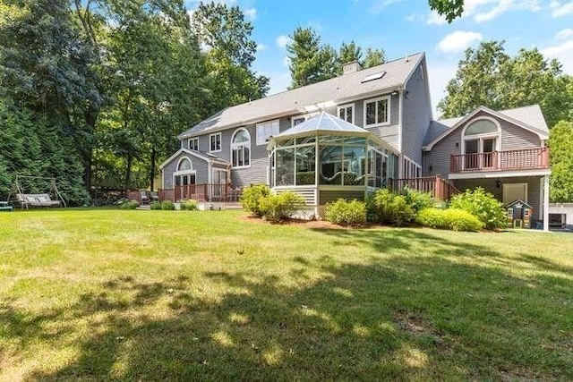 back of property with a yard, a deck, a sunroom, and a chimney
