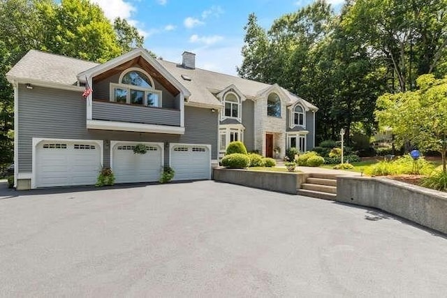 view of front of house with a garage, driveway, and a chimney