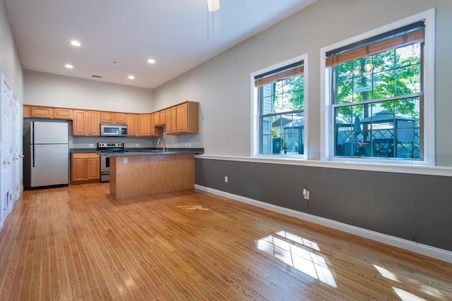 31-33 Ashland St Unit 5, Haverhill, MA 01830 - kitchen with stainless steel appliances, a sink, dark countertops, a peninsula, and light wood-type flooring