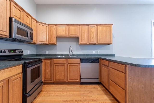 31-33 Ashland St Unit 5, Haverhill, MA 01830 - kitchen with appliances with stainless steel finishes, a sink, dark countertops, light wood finished floors, and a peninsula